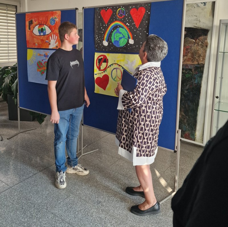 Oberbürgermeisterin Petra Becker unterhält sich mit Künstler und Schüler Marlon über sein eingereichtes Kunstwerk